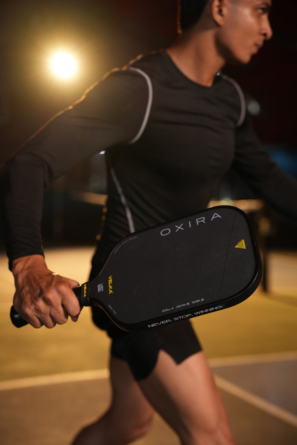 An athlete holding Velka Oxira pickleball paddle on a pickleball court.